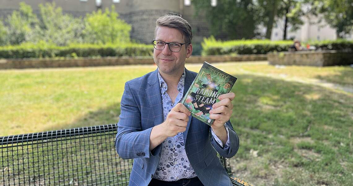 Person hält Buch in die Kamera